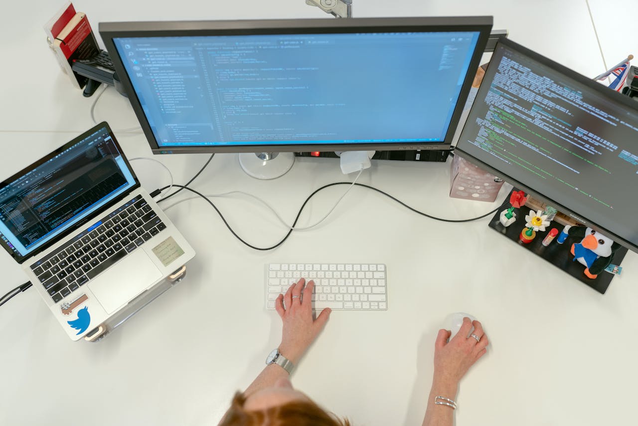 The Art of Drawing Readers In: Your attractive post title goes here A female software engineer coding on dual monitors and a laptop in an office setting.