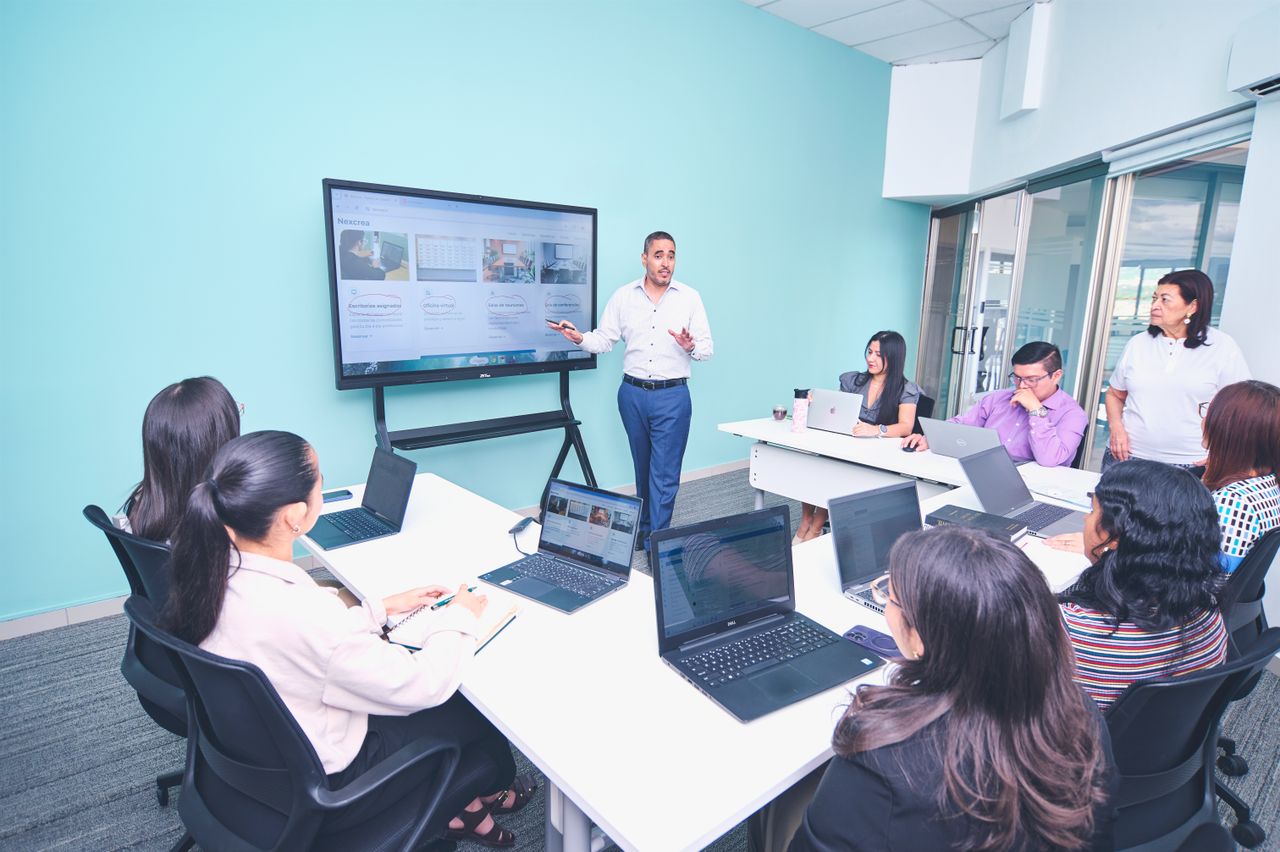 why-choose-us Team engaged in a presentation at a modern office using digital technology.
