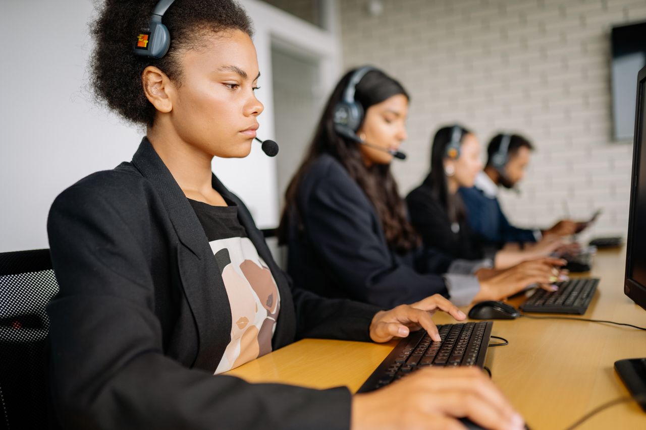 gallery-6 Diverse call center team working diligently on customer support with headsets and computers.